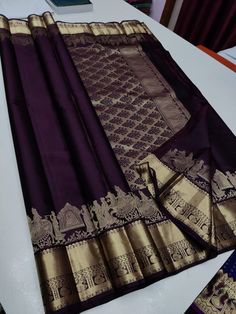 a purple and gold saree is laying on a white table with other items in the background