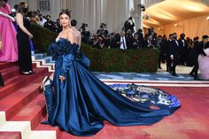 a woman in a blue gown is standing on some stairs and people are taking pictures