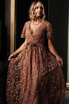 a woman wearing a brown dress standing in front of a doorway