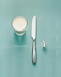 a knife, fork and glass of milk on a blue tablecloth with the tiffany & co logo