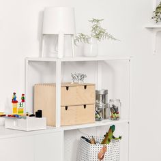 a white shelf filled with lots of toys and other items next to a lamp on top of a wall