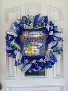 a blue and white christmas wreath hanging on a door with the words season's greetings