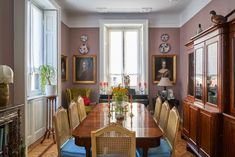 a dining room table with chairs and pictures on the wall in front of it's windows