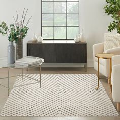 a living room filled with furniture and a white rug on top of a hard wood floor