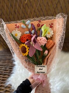 a hand holding a bouquet of flowers on top of a white furnishing area