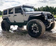 a white jeep parked on top of a dirt field