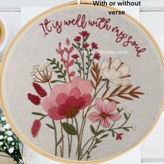 a close up of a embroidery on a table with a cup of coffee and flowers