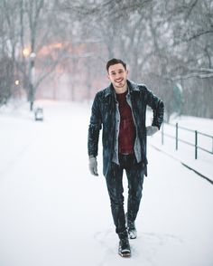 a man standing in the snow with his hands on his hips and smiling at the camera