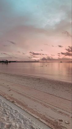 an empty beach at sunset with the sun going down and clouds in the sky above