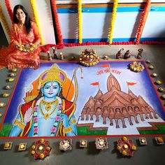 a woman sitting in front of a painting on the ground with other decorations around her