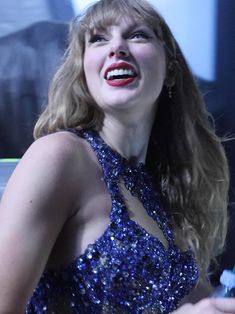 a woman in a blue dress laughing and holding a toothbrush with her mouth wide open