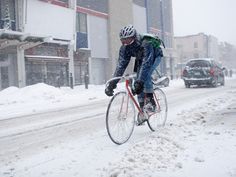 a man riding a bike down a snow covered street