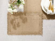 a place setting with napkins, silverware and flowers on a white table cloth