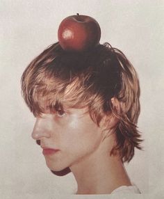 a young man with an apple on top of his head in front of a white background