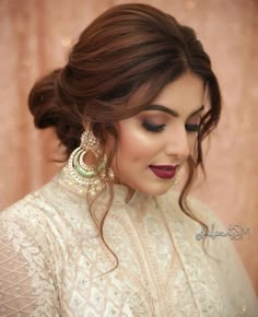 a woman with brown hair wearing earrings and a white dress