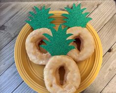 three doughnuts on a yellow plate with green glitter pineapple cutouts in the middle