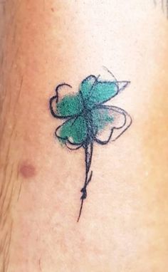 a small green flower tattoo on the side of a woman's neck and leg