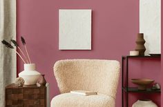 a living room with pink walls and white furniture, including a chair in the foreground