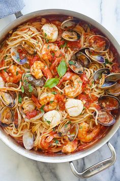 pasta with shrimp, clams and tomato sauce in a pan on a marble surface