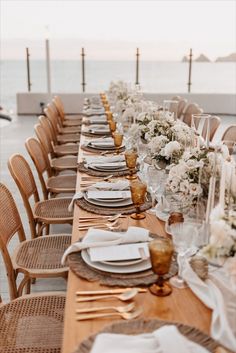 a long table set with place settings and flowers