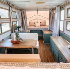 the interior of an rv with wood flooring and green cabinets, windows, and couches