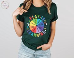 a woman wearing a green t - shirt with the words play is learning on it