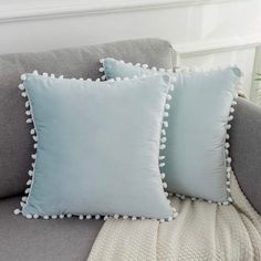 two blue pillows sitting on top of a gray couch