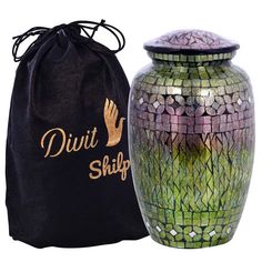 a green and purple vase next to a black bag with gold lettering on the side