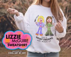 a woman wearing a white sweater with cartoon characters on it and the words, lizzie mccure sweatshirt designed by joy