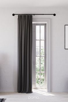 an open window with curtains hanging on it's side and a white wall in the background