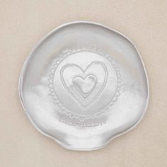 a silver plate with a heart on it and the words love is in the middle