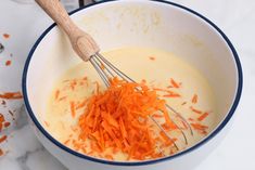 carrots being mixed in a bowl with a wooden spoon