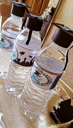 three bottled water bottles sitting on top of a table next to a mirror with black ribbon