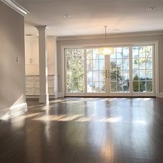 an empty living room with wood floors and french doors