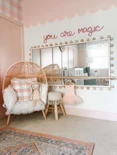 a pink and white bedroom with a mirror on the wall next to a chair in front of it