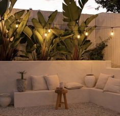 a white couch sitting on top of a gravel covered ground next to potted plants