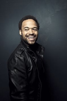 a smiling man in a black leather jacket