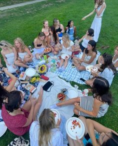 a group of women sitting on top of a grass covered field next to each other