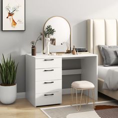 a bedroom with a bed, desk and mirror in it next to a potted plant