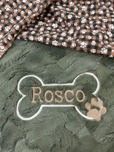 a close up of a dog's name and paw print on a green blanket