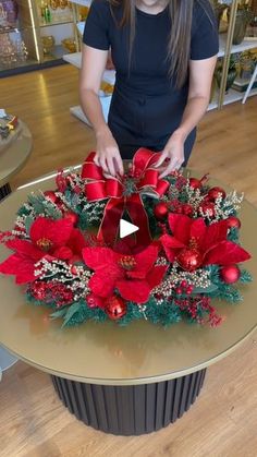 a woman is decorating a christmas wreath with poinsettis and greenery