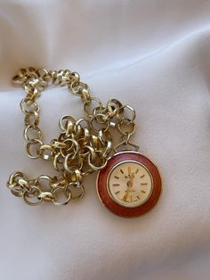 Elegant 1960's Vintage Art Deco Swiss women's Pendant Watch Wilson golden color case inlaid with apricot color enamel with clear white color dial. Very elegant classic present for women for every occasion. Collectible Swiss pendant ladies watch with new stainless steel necklace in golden color. An accent that would make every woman look stunning. Amazing present for vintage watch lovers. Very elegant classical gift for ladies. Pre-owned. The item has been used previously. It may have some signs of cosmetic wear but is fully operational and functions as intended. Checked and serviced. Exceptional gift for the loved one. The watch is in excellent condition and has no visible defects (please, see the pictures). Watch runs properly when tested. Should be wound up regularly on every 24 hours. T Vintage Pocket Watch Gift, Retro Gold-tone Jewelry For Gift, Retro Gold-tone Jewelry Gift, Gold Watches Suitable For Gifts, Gold Chain Watch As A Gift, Vintage Gold Round Watches, Retro Round Watch As Gift, Retro Round Watch For Gift, Vintage Metal Round Jewelry And Watches