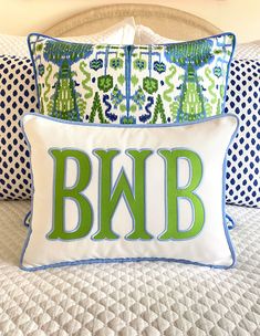 the monogrammed pillow is on top of the bed with blue and green pillows