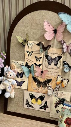 there are many butterflies on the wall next to a teddy bear and other items in front of it