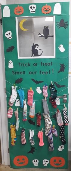 a green door decorated with halloween decorations and socks hanging from it's side, next to a sign that says trick or treat smell our feet