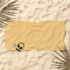 a pair of headphones laying on top of a towel in the middle of sand