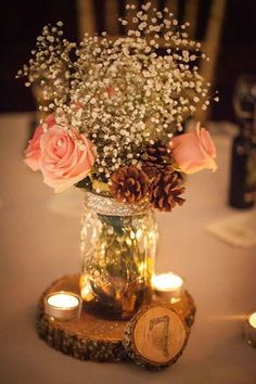 a vase filled with flowers sitting on top of a wooden table next to two candles