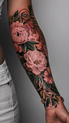 a woman's arm with pink flowers and leaves on the forearm, in front of her