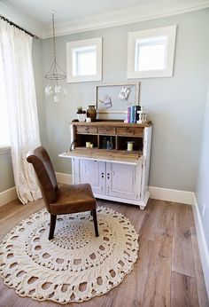 a chair sitting on top of a rug in front of a dresser and window sill