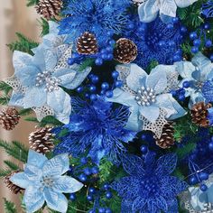 blue flowers and pine cones are arranged in a christmas tree with snowflakes on them